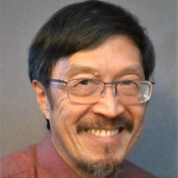 A middle-aged Asian man with black hair, a mustache, and a goatee wearing glasses and a salmon colored shirt