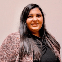 A woman with long black hair wearing a reddish sweater