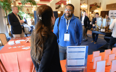a photo from a conference of someone talking to someone else at a vendor table