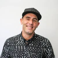 a man wearing a ball cap and a black shirt that has yellow bits throughout