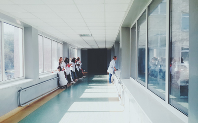 a hallway in a hospital ward, with several people in lab coats observing someone through glass